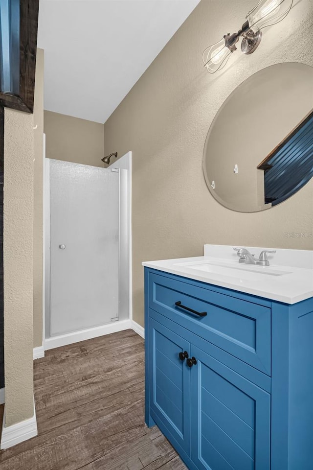 bathroom with hardwood / wood-style flooring, vanity, and a shower