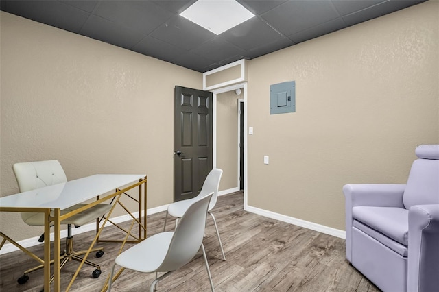 home office with hardwood / wood-style flooring, electric panel, and a drop ceiling