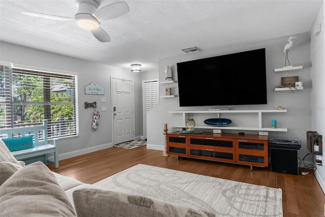 living room with ceiling fan, dark hardwood / wood-style flooring, and a textured ceiling