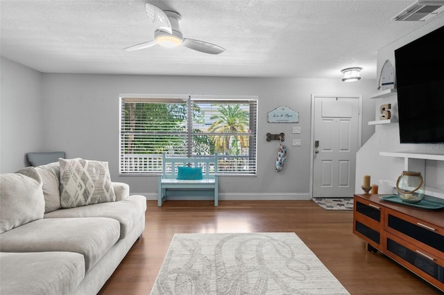 living room featuring ceiling fan, a textured ceiling, and dark hardwood / wood-style flooring