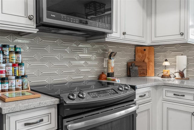 kitchen with stainless steel appliances, white cabinets, and decorative backsplash