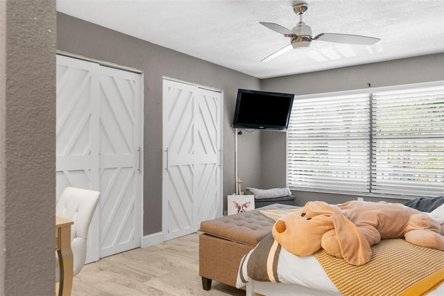 bedroom with ceiling fan, two closets, and a textured ceiling