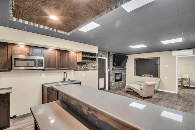 kitchen with a wall mounted air conditioner, light hardwood / wood-style floors, sink, and dark brown cabinets