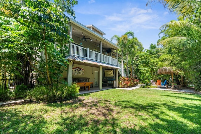 rear view of house featuring a balcony, a yard, ceiling fan, and a patio area