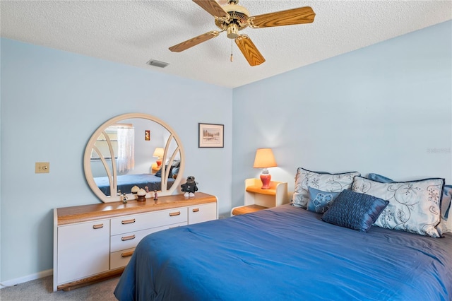 carpeted bedroom with ceiling fan and a textured ceiling