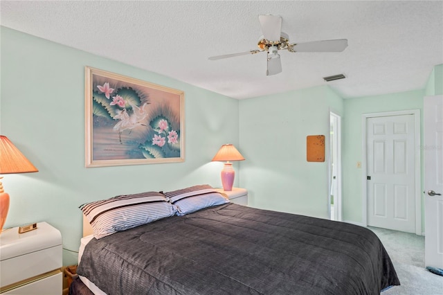 carpeted bedroom featuring ceiling fan and a textured ceiling