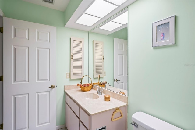 bathroom with vanity, a skylight, and toilet