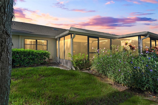 back house at dusk featuring a sunroom