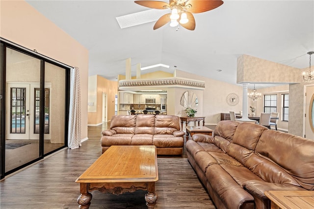 living room with ceiling fan with notable chandelier, dark wood-type flooring, and vaulted ceiling