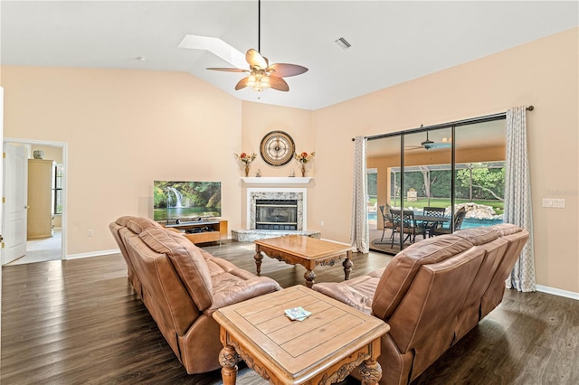 living room featuring lofted ceiling with skylight, a high end fireplace, dark wood-type flooring, and ceiling fan