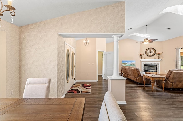 dining room featuring lofted ceiling, a high end fireplace, ceiling fan with notable chandelier, dark hardwood / wood-style floors, and decorative columns