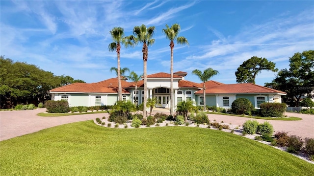 mediterranean / spanish home with a tiled roof, a front lawn, decorative driveway, and stucco siding