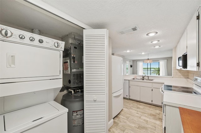 washroom featuring a textured ceiling, heating unit, sink, and stacked washer and clothes dryer