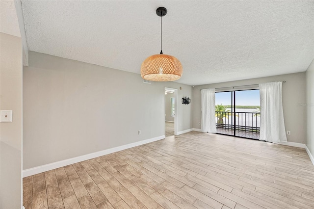 spare room featuring light hardwood / wood-style floors and a textured ceiling