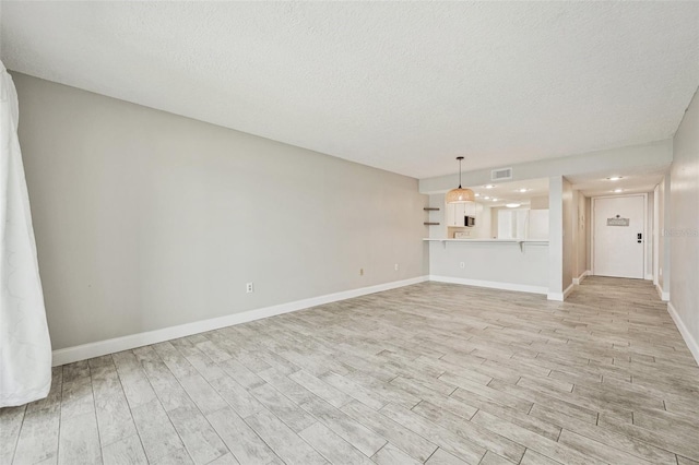 unfurnished living room with a textured ceiling and light hardwood / wood-style flooring