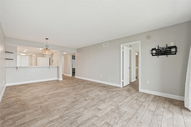 unfurnished living room with a textured ceiling and light hardwood / wood-style floors