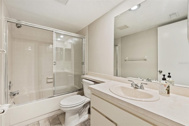 full bathroom featuring hardwood / wood-style flooring, bath / shower combo with glass door, vanity, a textured ceiling, and toilet