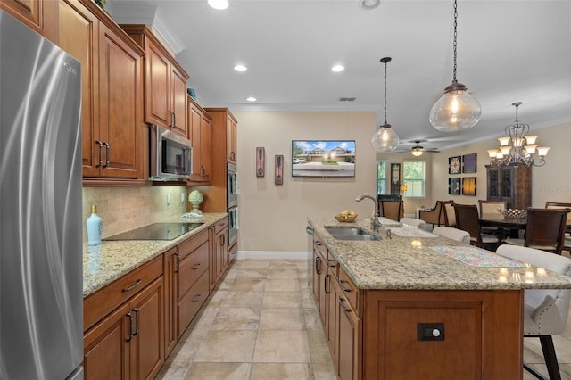 kitchen featuring a kitchen bar, appliances with stainless steel finishes, sink, a center island with sink, and decorative light fixtures