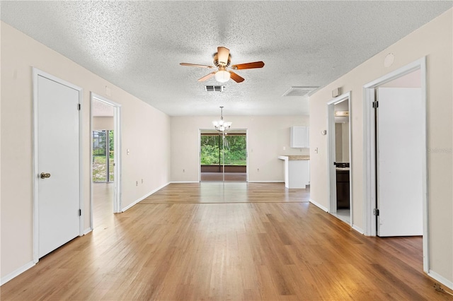 unfurnished room with light wood-type flooring, ceiling fan with notable chandelier, and a wealth of natural light