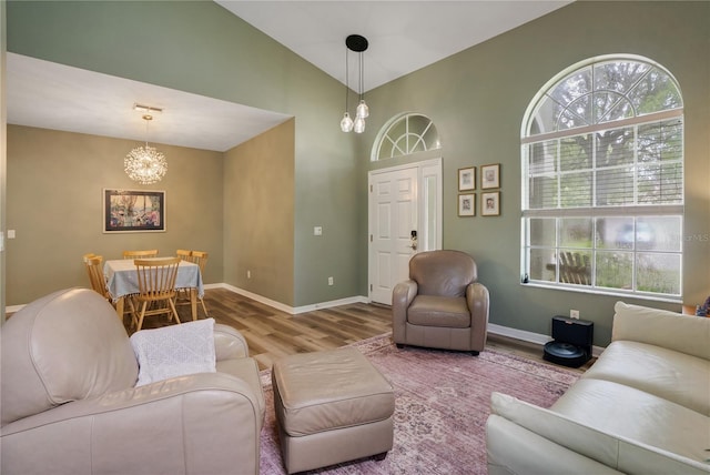 living room with high vaulted ceiling, wood-type flooring, and a notable chandelier