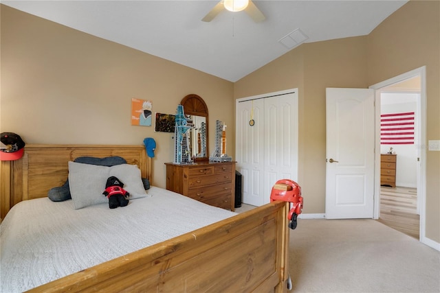 carpeted bedroom with ceiling fan, vaulted ceiling, and a closet