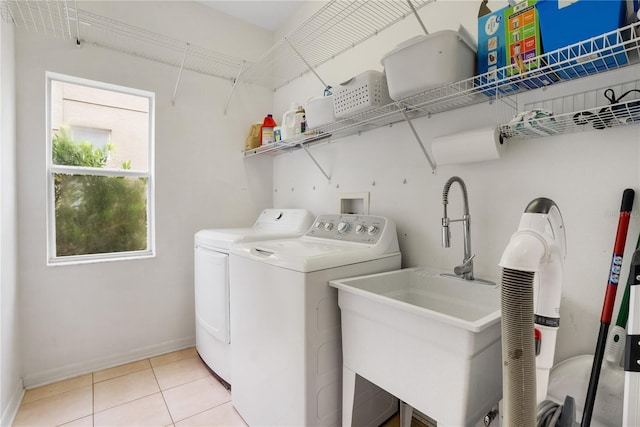 clothes washing area with light tile patterned flooring, independent washer and dryer, and sink