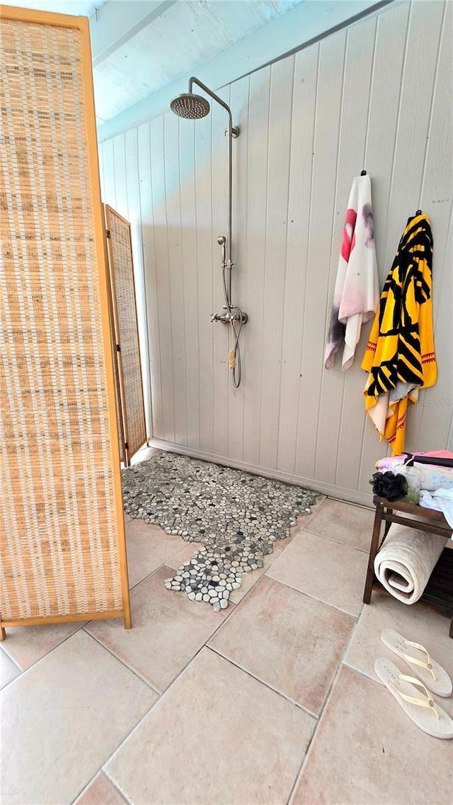 full bathroom featuring tile patterned flooring, wooden walls, and a shower