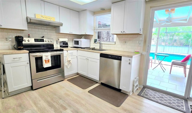 kitchen featuring light wood-type flooring, under cabinet range hood, stainless steel appliances, and a sink