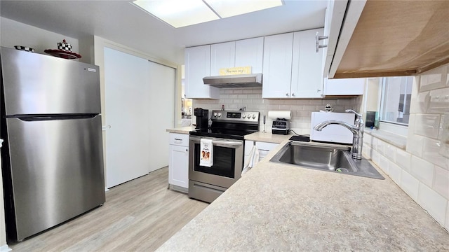 kitchen featuring decorative backsplash, appliances with stainless steel finishes, white cabinets, a sink, and under cabinet range hood