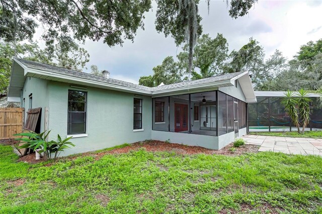 back of property featuring a lanai, a sunroom, a swimming pool, and a lawn
