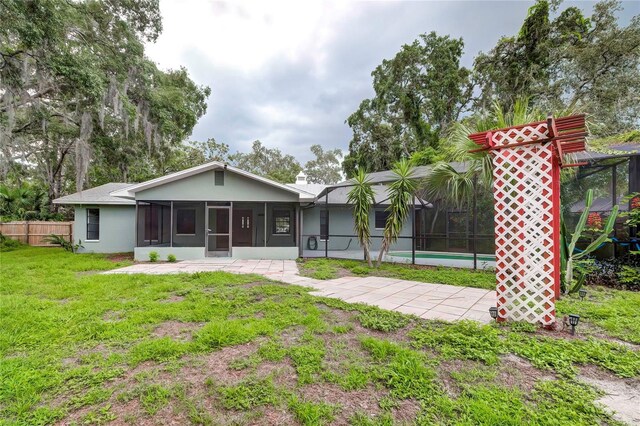 rear view of house featuring a sunroom, a yard, and a swimming pool