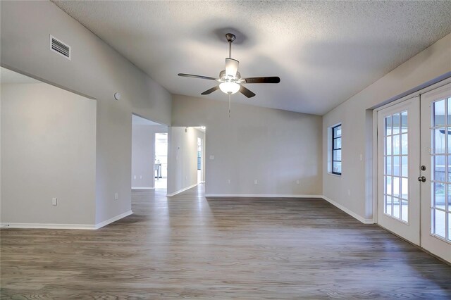 unfurnished room featuring ceiling fan, french doors, hardwood / wood-style floors, a textured ceiling, and lofted ceiling