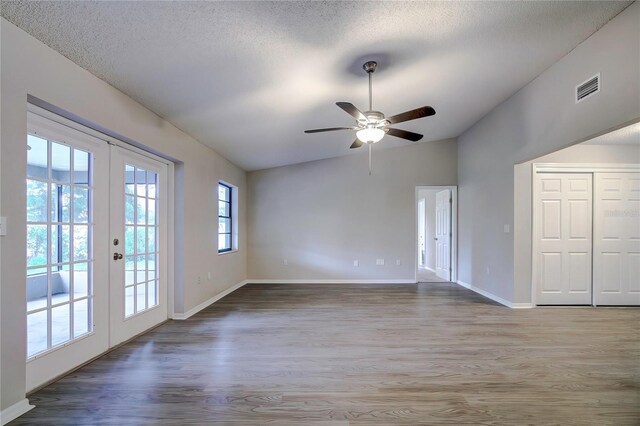 empty room with lofted ceiling, french doors, ceiling fan, a textured ceiling, and wood-type flooring