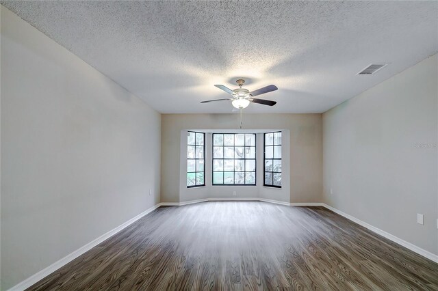 unfurnished room featuring ceiling fan, dark hardwood / wood-style flooring, and a textured ceiling