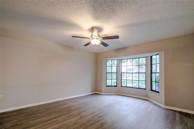 unfurnished room featuring dark hardwood / wood-style floors, ceiling fan, and a textured ceiling