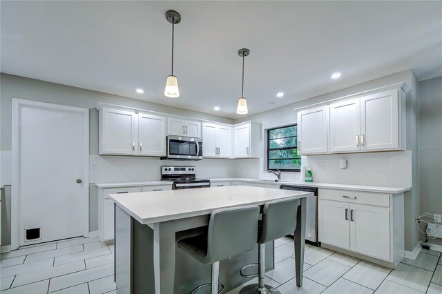 kitchen with white cabinets, sink, stainless steel appliances, and hanging light fixtures