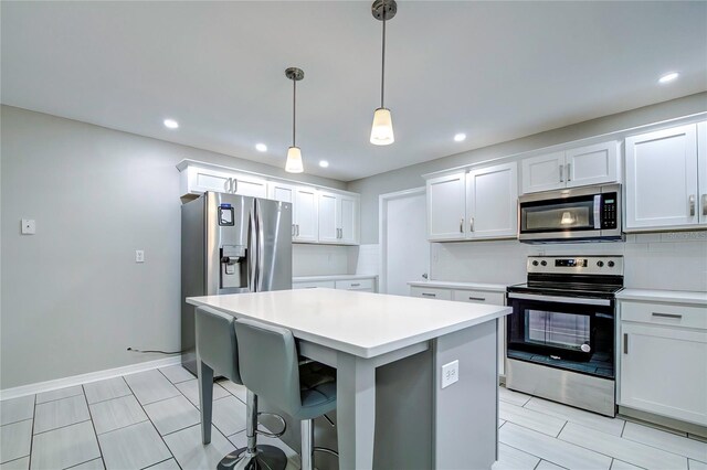 kitchen featuring appliances with stainless steel finishes, a kitchen breakfast bar, decorative light fixtures, white cabinets, and a center island