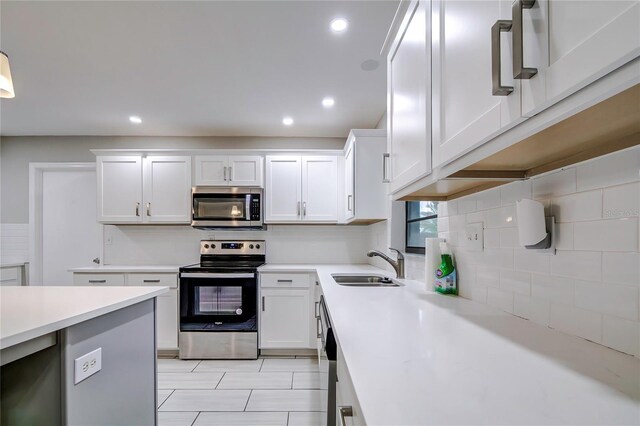 kitchen featuring tasteful backsplash, white cabinetry, sink, and appliances with stainless steel finishes
