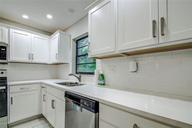 kitchen with white cabinets, decorative backsplash, stainless steel appliances, and sink