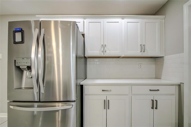 kitchen with white cabinets, stainless steel fridge, and decorative backsplash