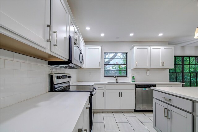kitchen with decorative backsplash, white cabinetry, sink, and appliances with stainless steel finishes