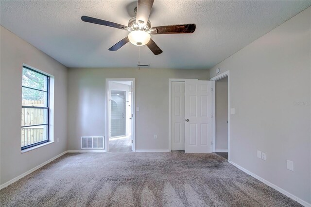 unfurnished bedroom with a textured ceiling, carpet floors, and ceiling fan