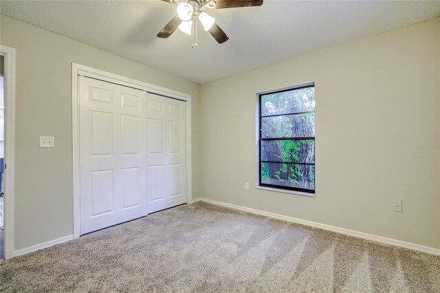 unfurnished bedroom featuring ceiling fan, a closet, and carpet