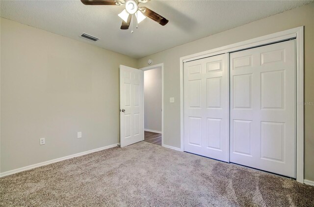 unfurnished bedroom with light carpet, a textured ceiling, a closet, and ceiling fan