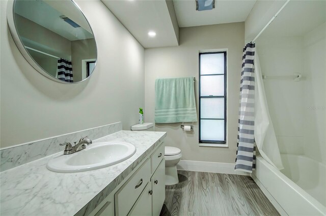 full bathroom with hardwood / wood-style flooring, vanity, shower / bath combo, and toilet