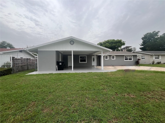 rear view of property with a carport and a yard