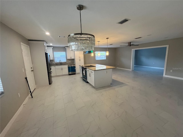 kitchen with a center island, sink, hanging light fixtures, stainless steel appliances, and white cabinets