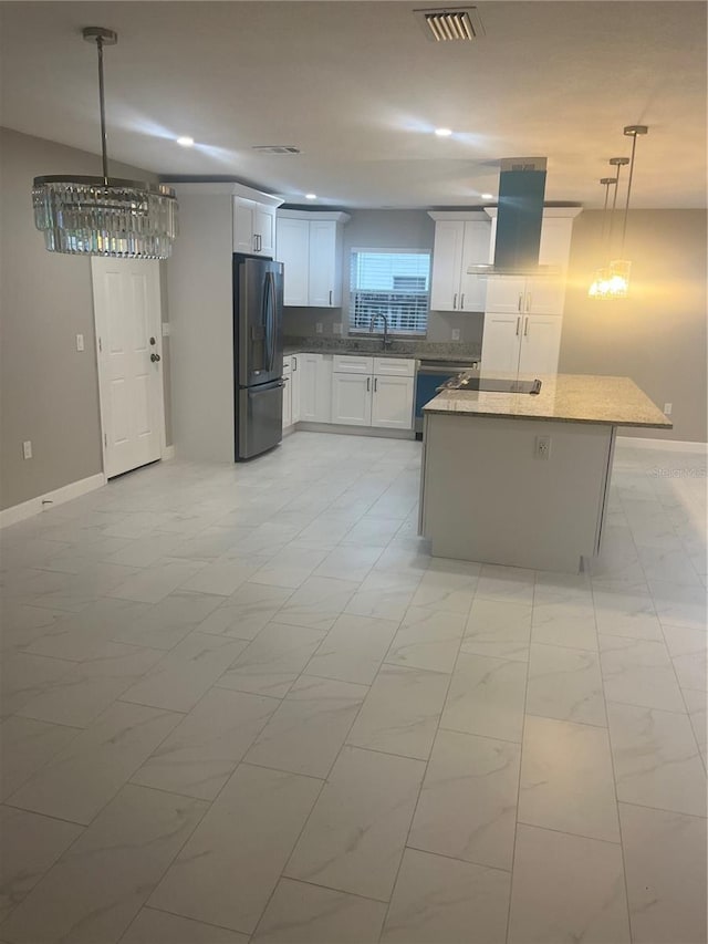 kitchen featuring sink, wall chimney exhaust hood, stainless steel appliances, decorative light fixtures, and a kitchen island