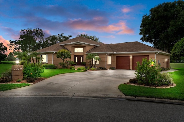 prairie-style home with a garage and a lawn