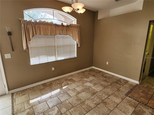 spare room with tile patterned flooring, a textured ceiling, and an inviting chandelier